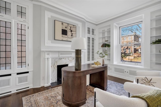 office with built in shelves, a premium fireplace, dark wood-type flooring, and ornamental molding