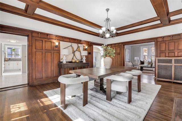 dining area featuring coffered ceiling, dark hardwood / wood-style flooring, ornamental molding, and an inviting chandelier