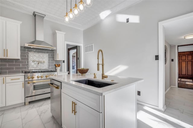 kitchen featuring white cabinetry, wall chimney range hood, sink, and appliances with stainless steel finishes