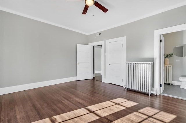 empty room with radiator heating unit, dark hardwood / wood-style flooring, ceiling fan, and crown molding