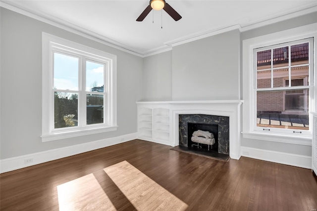 unfurnished living room with a high end fireplace, dark hardwood / wood-style floors, ceiling fan, and crown molding