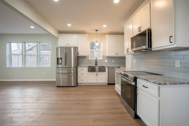 kitchen featuring white cabinets, pendant lighting, sink, and appliances with stainless steel finishes