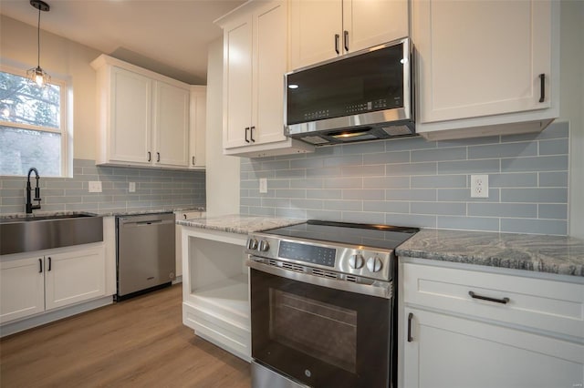 kitchen with white cabinetry, sink, stainless steel appliances, backsplash, and light wood-type flooring