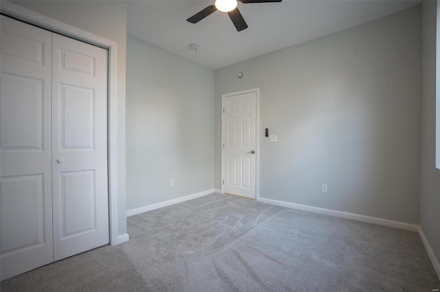 unfurnished bedroom featuring ceiling fan, a closet, and light carpet