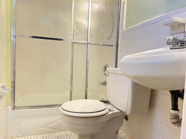 bathroom featuring tile patterned floors, a shower with shower door, tile walls, and toilet