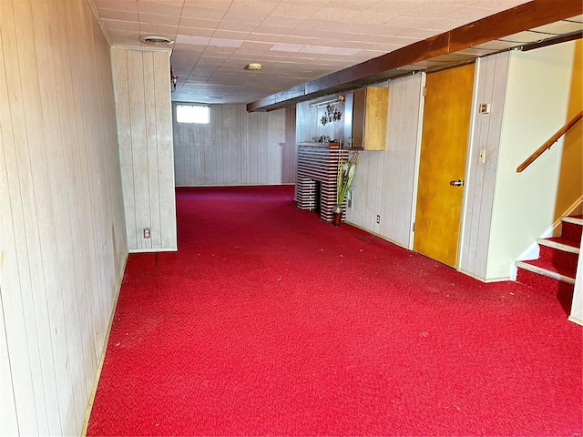 basement featuring wooden walls and dark colored carpet