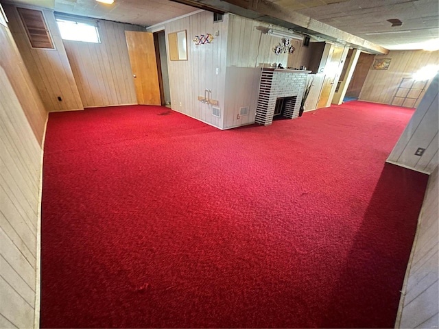 basement featuring carpet, wood walls, and a fireplace