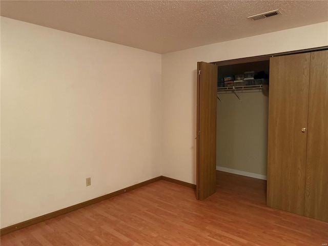 unfurnished bedroom with hardwood / wood-style flooring, a textured ceiling, and a closet