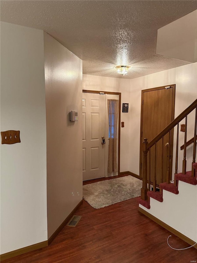 entrance foyer with dark hardwood / wood-style flooring and a textured ceiling