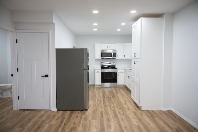 kitchen with white cabinets, appliances with stainless steel finishes, and light hardwood / wood-style flooring