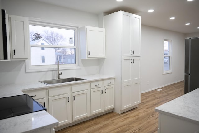 kitchen with light hardwood / wood-style floors, stainless steel refrigerator, a healthy amount of sunlight, and sink