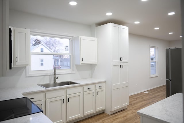 kitchen featuring white cabinets, light hardwood / wood-style floors, sink, and stainless steel refrigerator