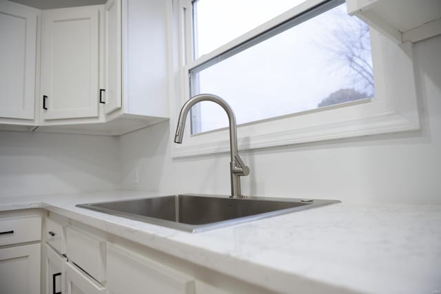 kitchen featuring white cabinetry, sink, and light stone counters