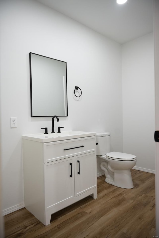 bathroom with wood-type flooring, vanity, and toilet