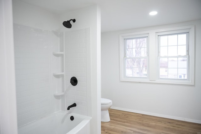 bathroom featuring wood-type flooring, tiled shower / bath combo, and toilet