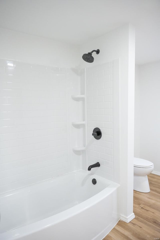 bathroom with hardwood / wood-style floors, toilet, and tiled shower / bath