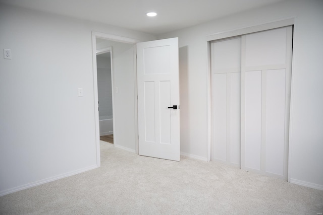 unfurnished bedroom featuring a closet and light colored carpet