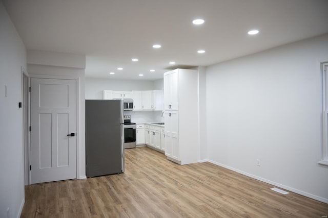 kitchen with white cabinets, stainless steel appliances, and light hardwood / wood-style flooring