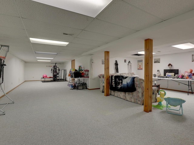 finished below grade area featuring carpet, a drop ceiling, visible vents, and baseboards