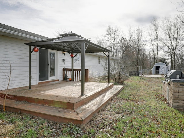 wooden deck featuring an outbuilding, a gazebo, a storage unit, and fence