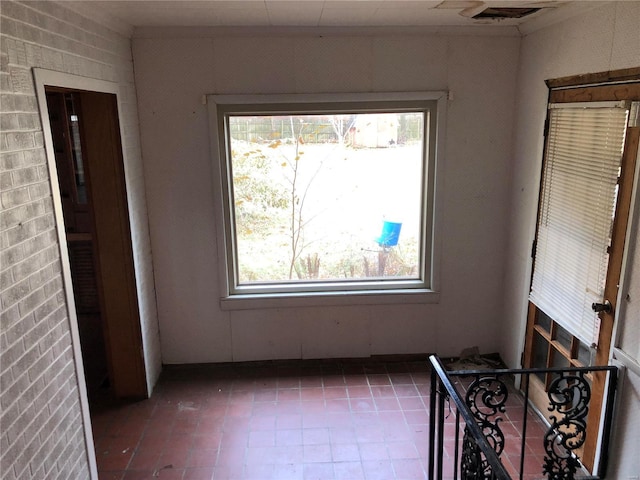 spare room featuring plenty of natural light and brick wall