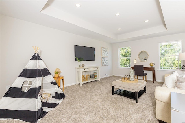 carpeted living room with a tray ceiling