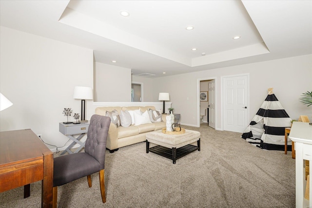 carpeted living room with a tray ceiling