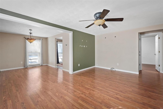 unfurnished living room with ceiling fan, baseboards, and wood finished floors