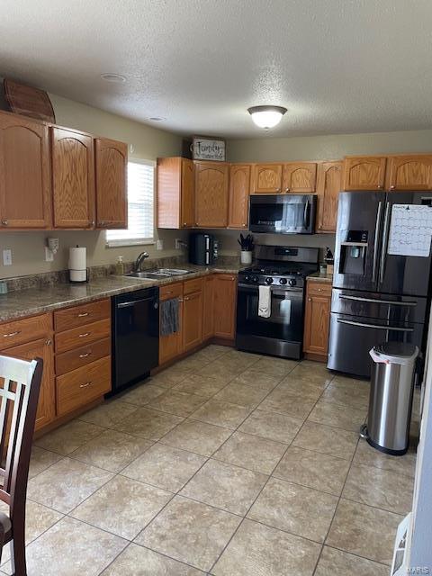 kitchen with sink, light tile patterned flooring, black appliances, and a textured ceiling