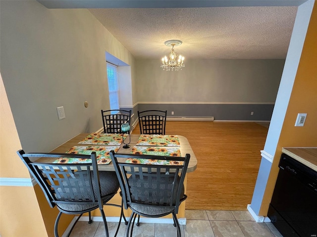 dining area with a notable chandelier, light wood-type flooring, a textured ceiling, and baseboard heating