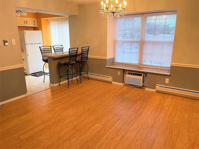 dining room with light wood-type flooring, baseboard heating, an AC wall unit, and a chandelier