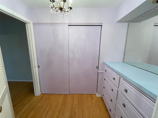 walk in closet with light hardwood / wood-style floors and an inviting chandelier