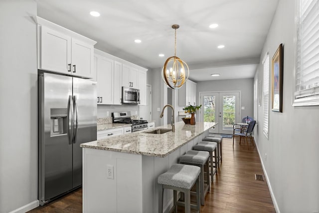 kitchen featuring stainless steel appliances, white cabinetry, hanging light fixtures, and sink