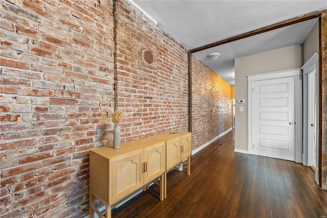 hall with dark wood-type flooring and brick wall