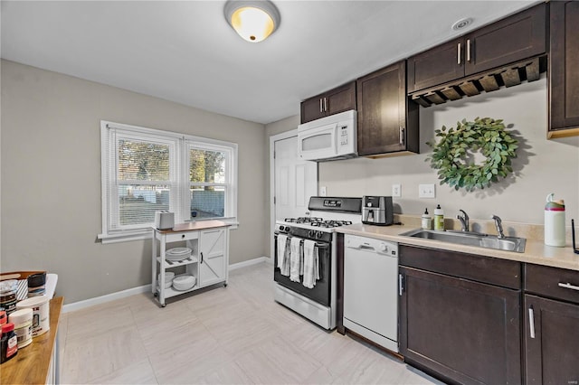 kitchen with dark brown cabinets, white appliances, and sink