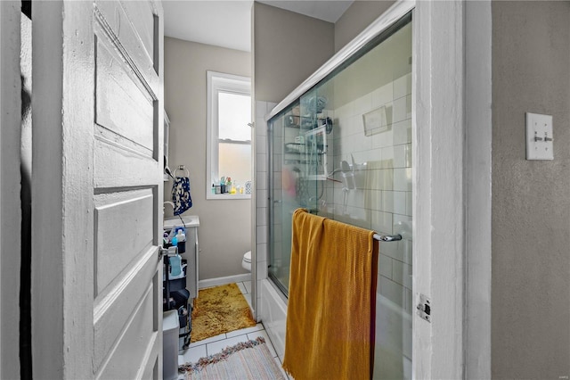 bathroom featuring shower / bath combination with glass door, tile patterned floors, and toilet