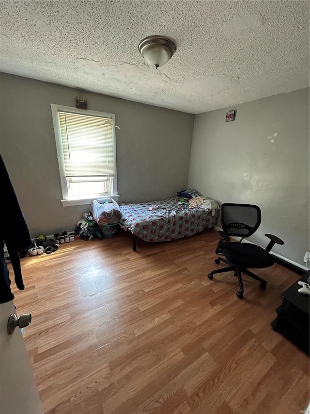 bedroom featuring light hardwood / wood-style floors and a textured ceiling