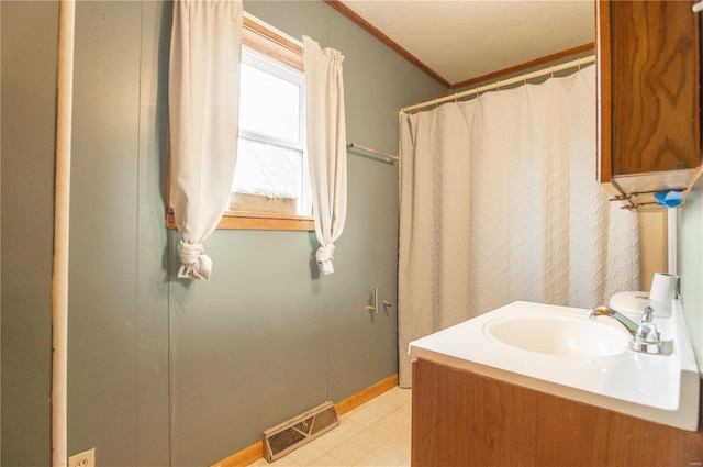 bathroom with a textured ceiling, vanity, and crown molding