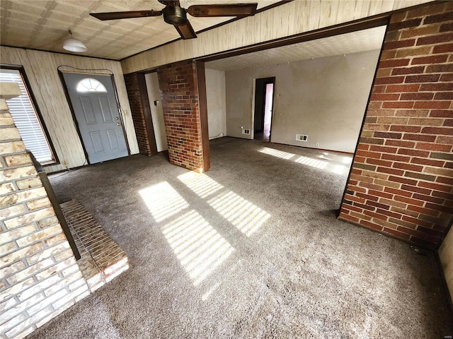 carpeted foyer with ceiling fan and wood walls