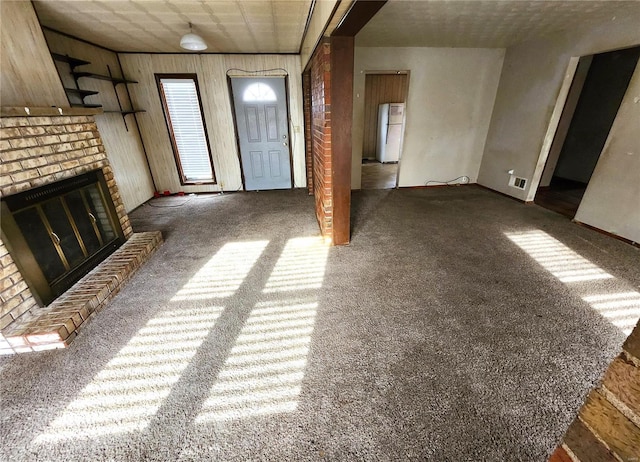 unfurnished living room featuring wood walls, a fireplace, and dark carpet