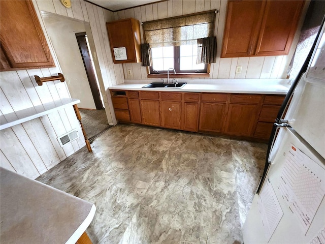 kitchen with wood walls, sink, and fridge