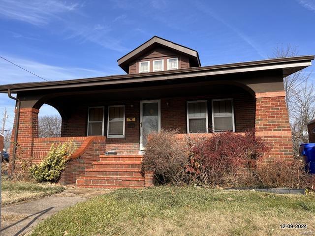 bungalow-style house featuring a porch and a front lawn