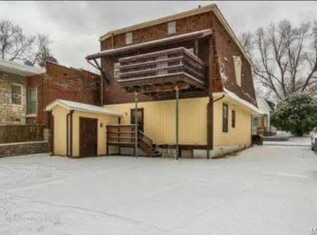 snow covered back of property with a balcony