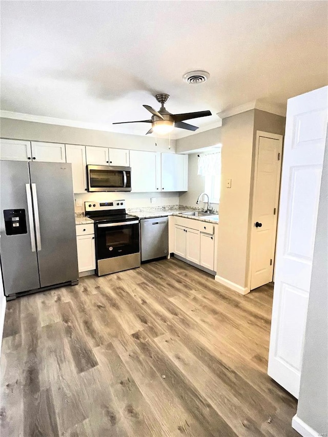 kitchen featuring white cabinets, crown molding, ceiling fan, appliances with stainless steel finishes, and wood-type flooring