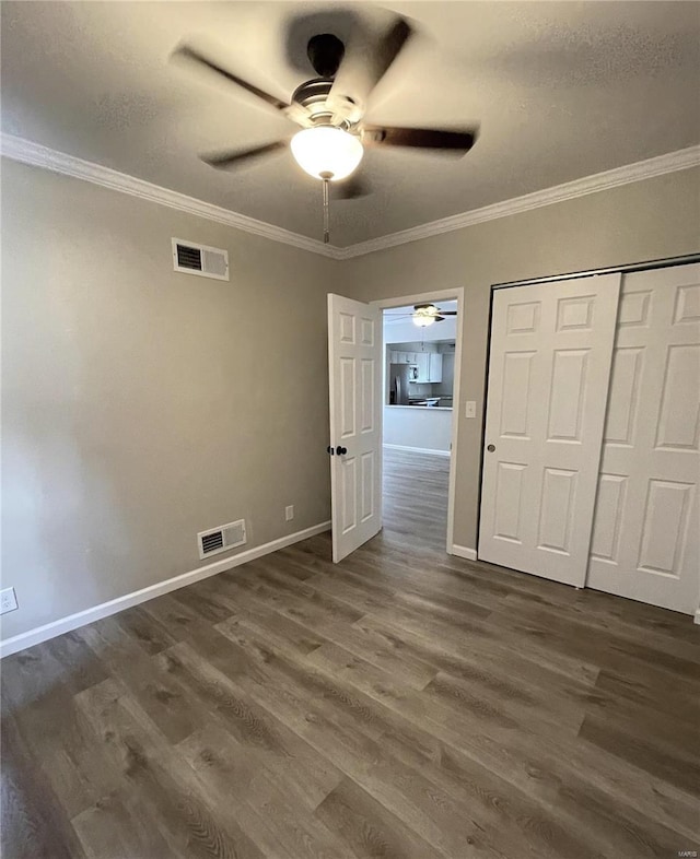 unfurnished bedroom featuring dark hardwood / wood-style flooring, a closet, ceiling fan, and ornamental molding