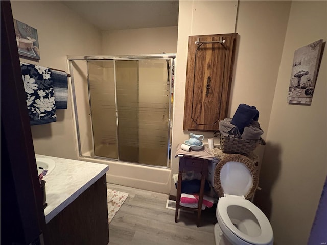 full bathroom with hardwood / wood-style floors, vanity, toilet, and enclosed tub / shower combo