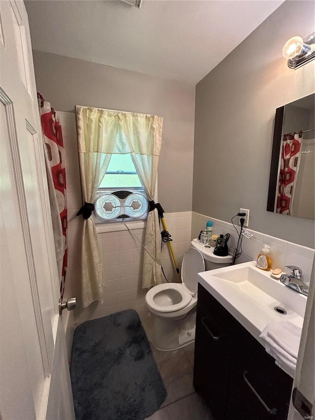 bathroom with tile patterned flooring, vanity, toilet, and tile walls