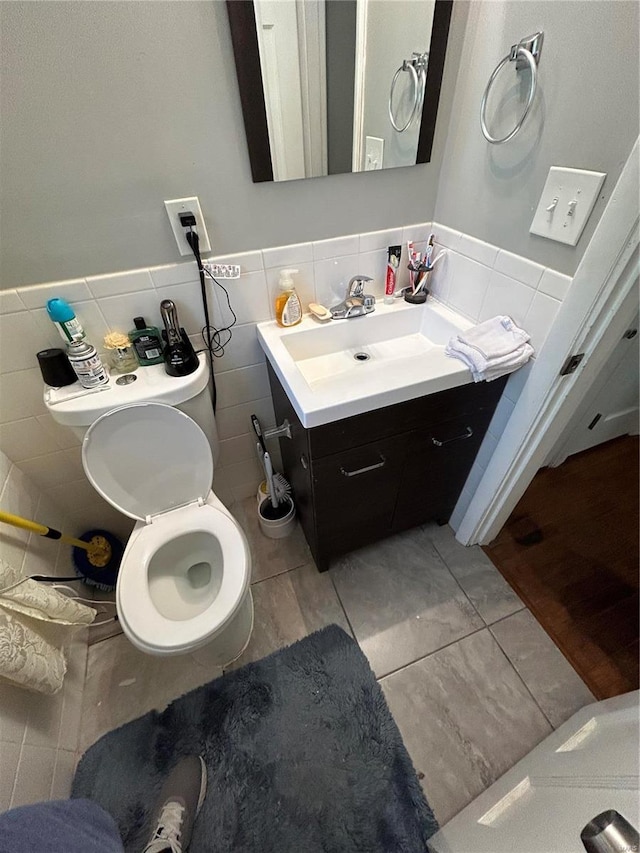 bathroom featuring tile patterned floors, vanity, toilet, and tile walls