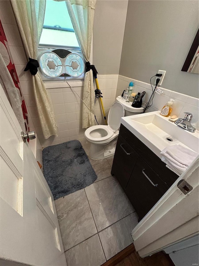 bathroom featuring tile patterned flooring, vanity, tile walls, and toilet