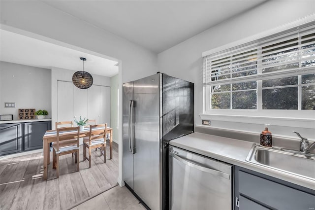 kitchen with appliances with stainless steel finishes, light countertops, a sink, and gray cabinetry